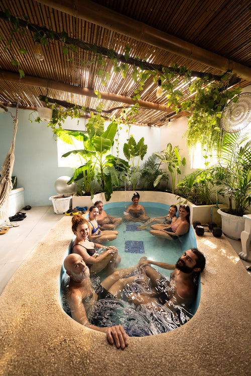 Group of people relaxing in a hot tub surrounded by lush greenery