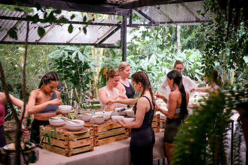Guests at Vida Asana retreat center in Costa Rica serving themselves from a buffet of healthy, organic food in an open-air dining area surrounded by jungle foliage.