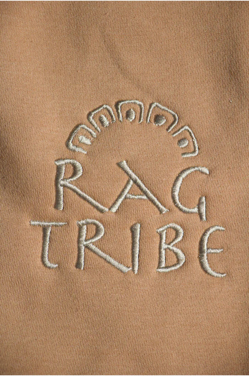 Embroidered 'RAG TRIBE' logo on a brown fabric background