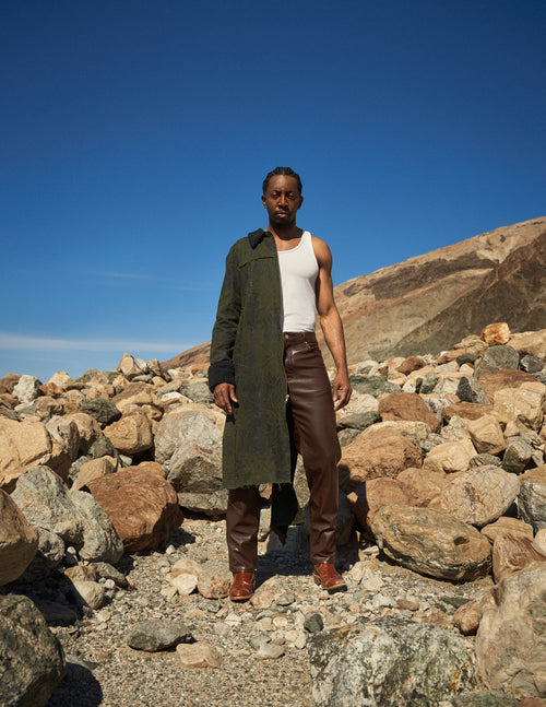 Man modeling Ragtribe coat on rocks.